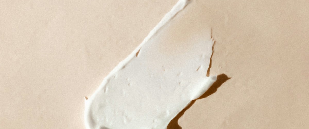 Creme facial espalhado sobre superfície bege